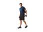 Un homme portant un t-shirt de vélo bleu marine et un short noir, transporte un casque de vélo.
