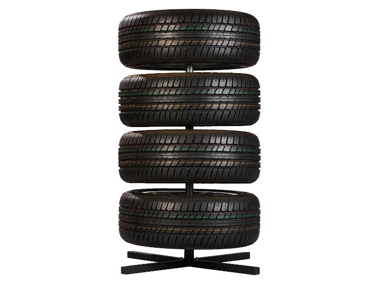 Quatre pneus de voiture empilés verticalement sur un support noir.