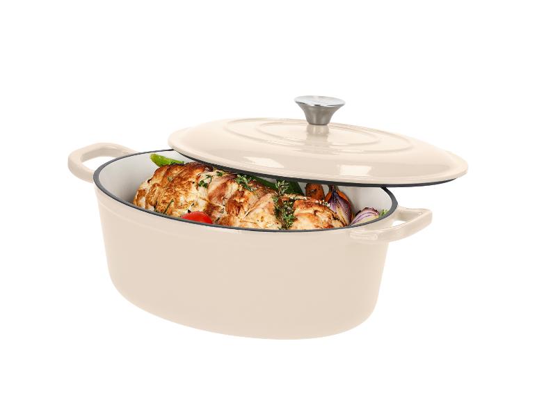 Cocotte ovale en fonte beige avec couvercle, remplie de viande rôtie et de légumes.