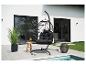 Fauteuil suspendu noir avec coussin sur une terrasse au bord d'une piscine, avec plantes et table d'appoint.