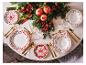 Table de Noël dressée avec des assiettes et des couverts rouges et dorés.