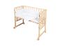 Lit bébé en bois sur roulettes avec literie blanche à motifs d'étoiles et de lunes.