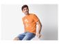 Homme portant un t-shirt orange Voyager avec imprimé palmiers et un short en jean.