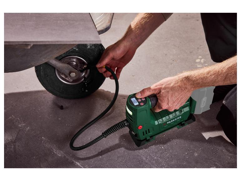 Un homme gonfle la roue d'une brouette avec un compresseur portable Parkside.