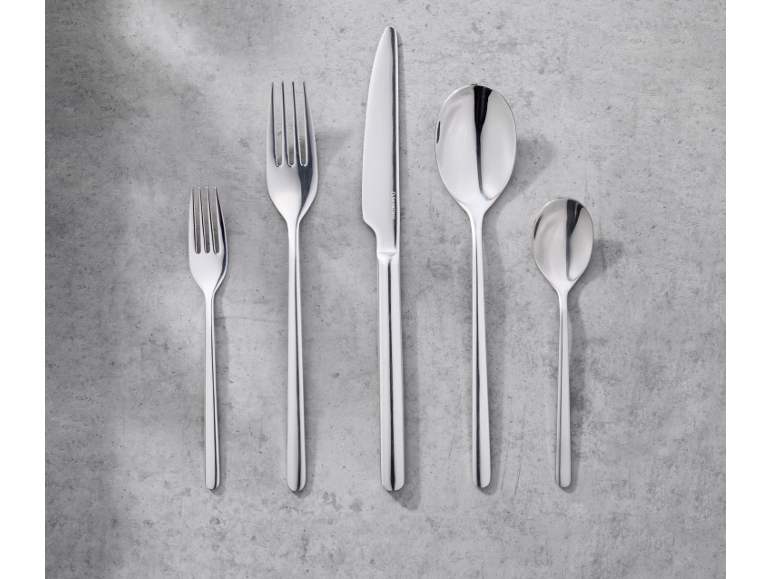 Ensemble de couverts en acier inoxydable: deux fourchettes, un couteau et deux cuillères sur fond gris.