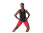 Femme en débardeur noir et short de sport rouge, faisant de l'exercice.