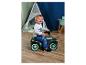 Enfant en bas âge conduisant une voiture à pousser dans une chambre avec une tente de jeu.