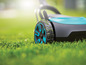 Un robot tondeuse sur l'herbe, avec un design bleu et noir.