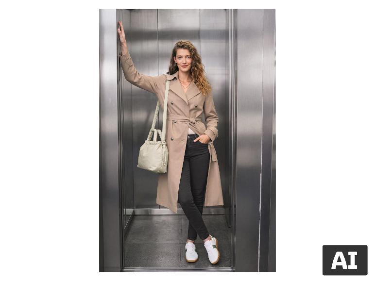 Femme en trench-coat beige, jean noir et baskets blanches dans un ascenseur.
