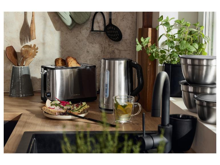 Un grille-pain et une bouilloire en acier inoxydable sur un comptoir de cuisine en bois, avec du pain grillé et du thé.