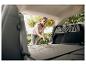 Femme passant l'aspirateur dans le coffre sale d'une voiture avec un aspirateur à main.