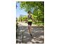 Femme en t-shirt de sport et short de course, avec un sac à dos de running, courant dans un parc.