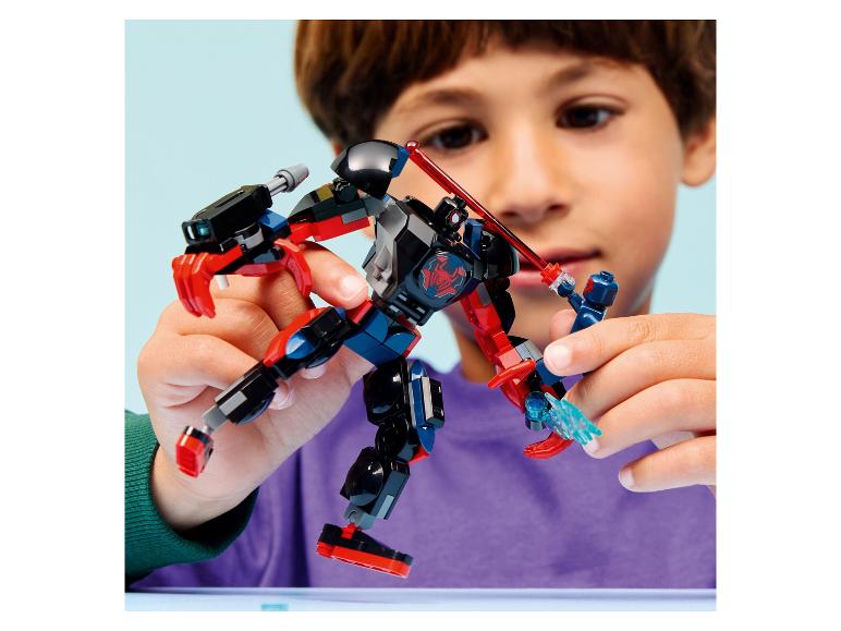 Un enfant joue avec un robot jouet noir et rouge et une petite figurine bleue.