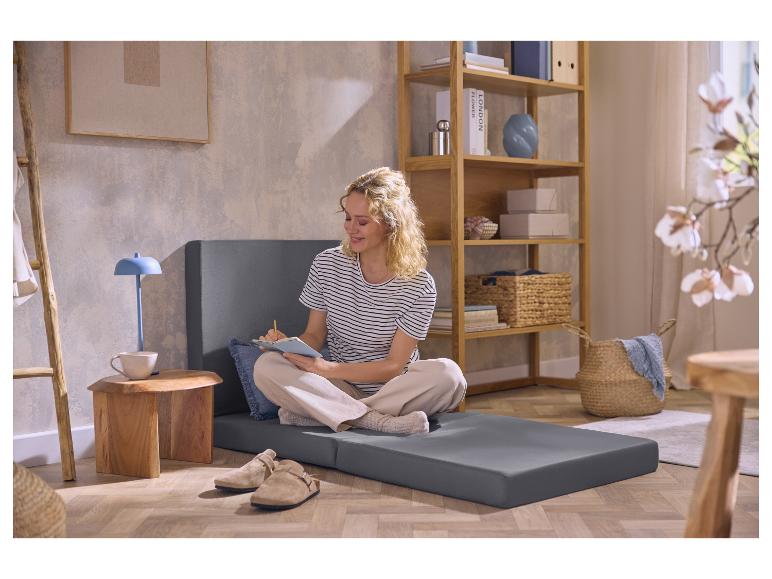 Femme assise sur le matelas pliant gris 2-en-1 de LIVARNO home.