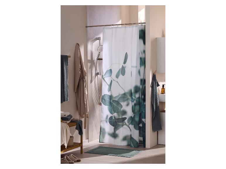 Salle de bain avec rideau de douche à feuilles d'eucalyptus, serviettes et tapis de bain.