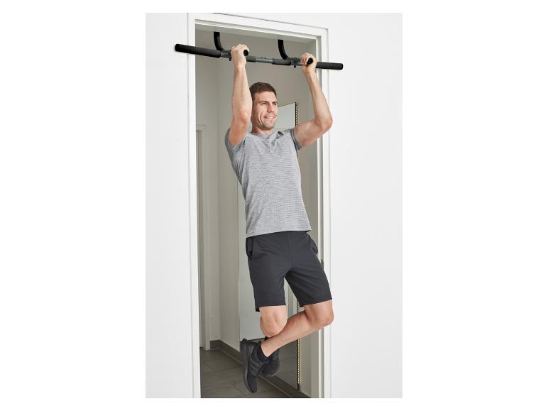 Un homme s'entraîne sur une barre de traction fixée sur une porte.