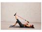 Une femme fait des exercices avec un élastique de résistance sur un tapis de yoga.