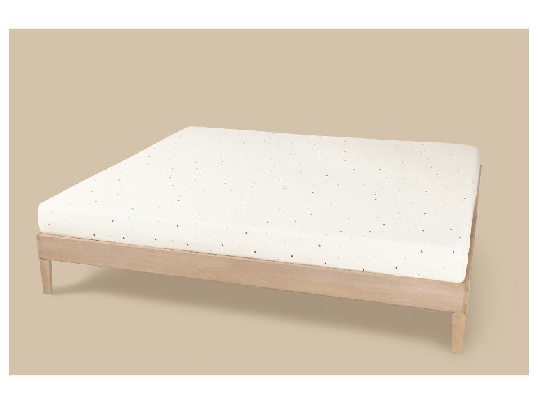 Cadre de lit en bois avec un matelas blanc à pois colorés.
