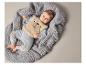Bébé portant des vêtements gris avec un ours, couché sur une couverture grise.