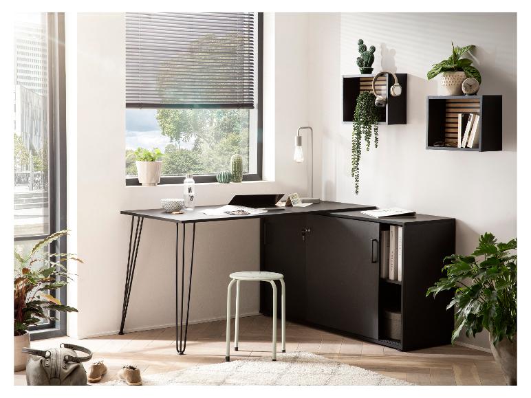 Bureau d'angle noir avec rangement, tabouret vert clair et plantes dans un bureau lumineux.