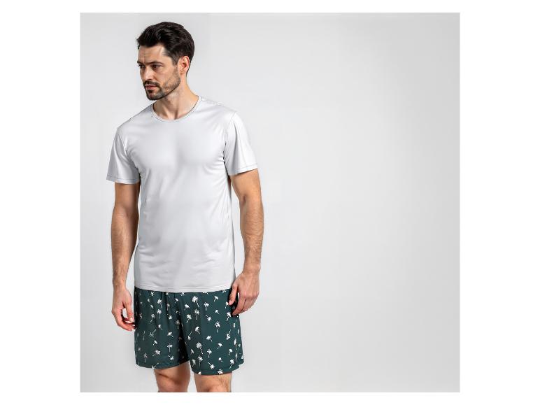 Homme en t-shirt blanc et short de bain imprimé palmiers.