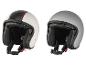 Deux casques de moto rétro, un blanc à rayures rouges et un gris.