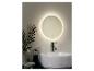 Un miroir rond éclairé au-dessus d'un lavabo dans une salle de bain.