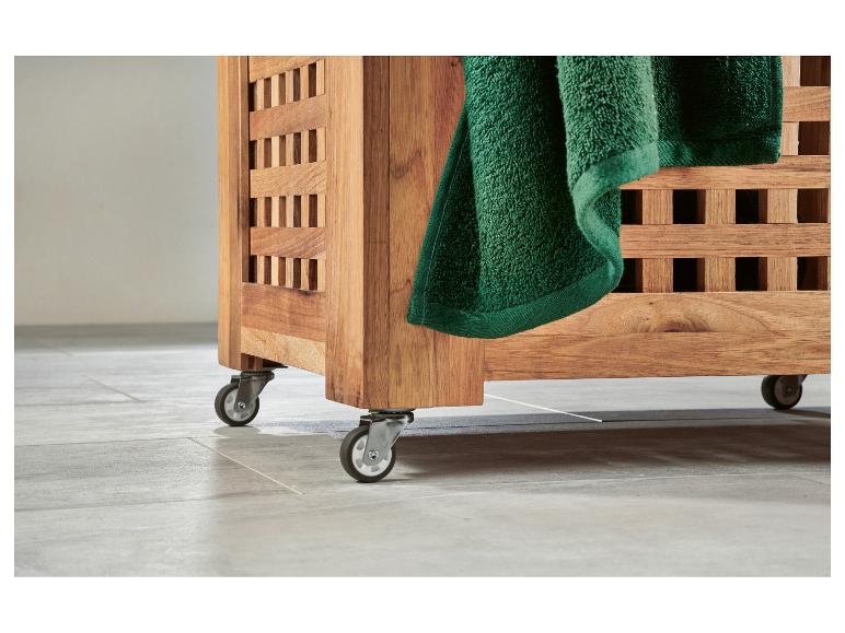 Panier à linge en bois sur roulettes, avec une serviette verte suspendue.