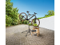 Vélo électrique sur un support de réparation avec des outils sur un tabouret en bois.