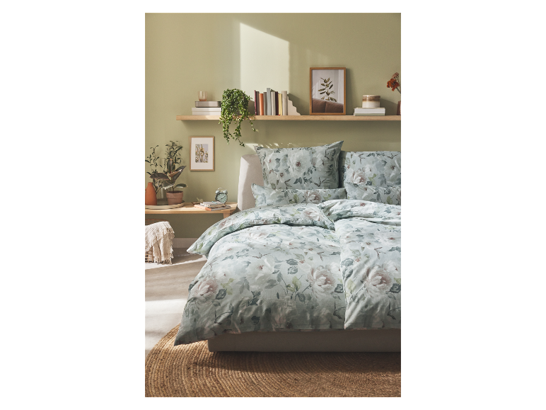 Parure de lit fleurie aux tons verts et roses sur un lit dans une chambre à coucher au style moderne.