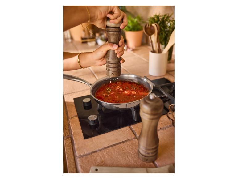 Préparation d'une sauce tomate ; moulins à poivre en bois.