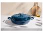 Cocotte en fonte bleue sur un comptoir en marbre avec planche à découper et bouteille d'huile.