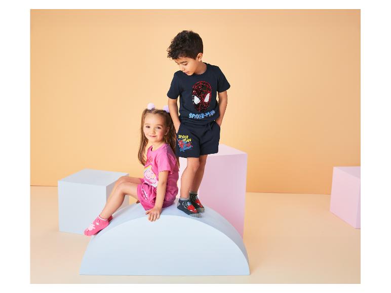 Deux enfants, une fille et un garçon, portent des t-shirts et des shorts à motifs de personnages de dessins animés.