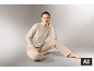 Une femme vêtue d'un ensemble d'intérieur beige assise sur un fond gris