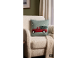 Coussin vert avec camion de Noël rouge et sapin sur un fauteuil beige.