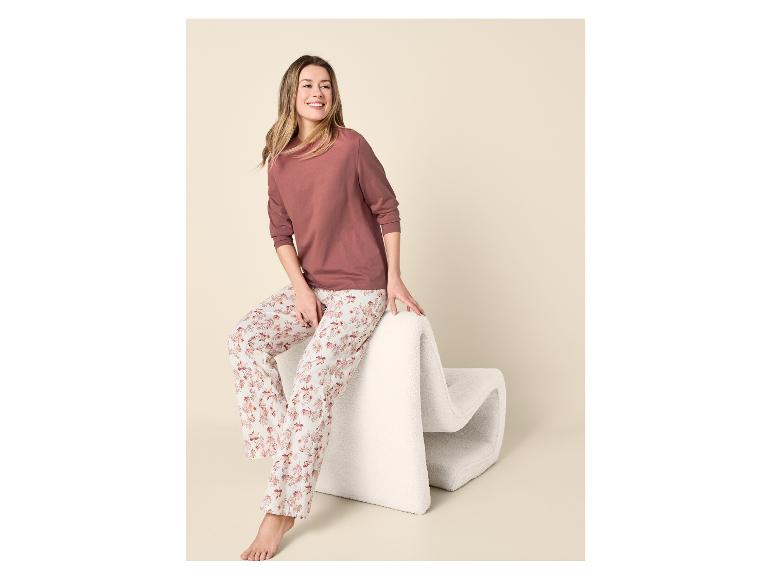Femme en haut à manches longues et pantalon de pyjama à motifs, assise sur une chaise blanche.