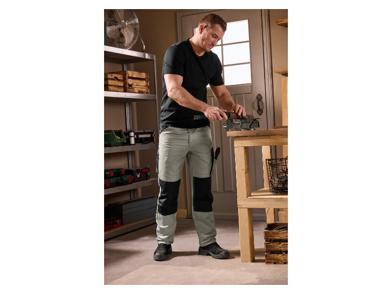Homme en pantalon de travail PARKSIDE® travaillant le bois dans un atelier.