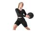 Femme en tenue de sport noire tenant un ballon lesté noir.