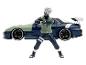 Une figurine de Kakashi de Naruto à côté d'une voiture de sport bleue.
