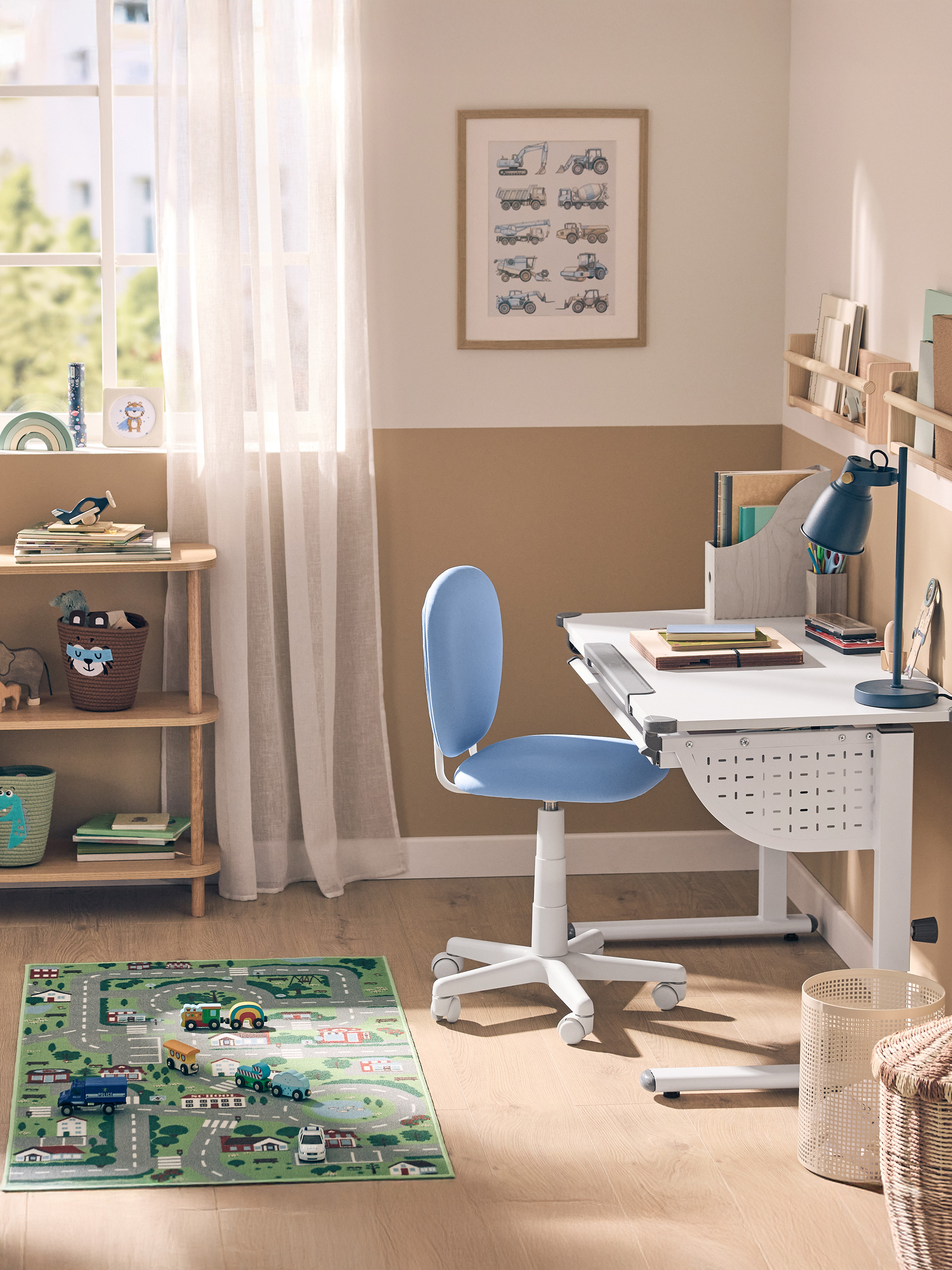 Chambre d'enfant avec un bureau blanc, une chaise bleue, une étagère en bois et un tapis de jeu.