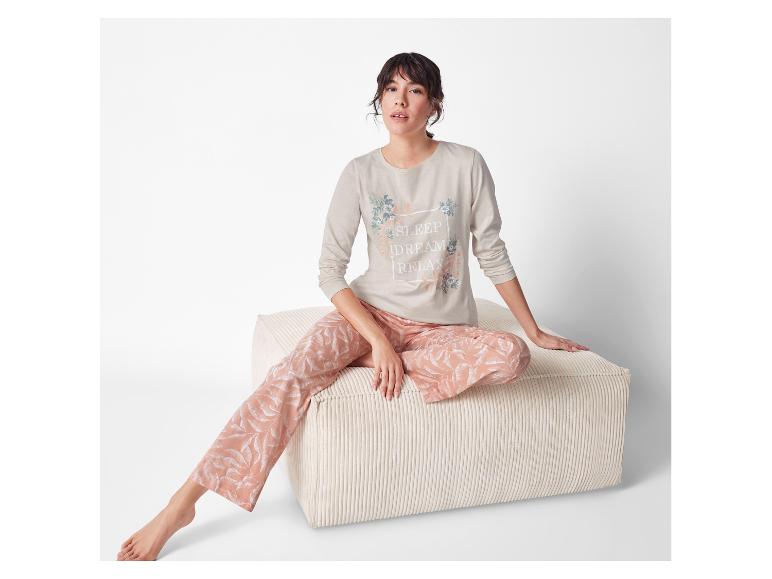 Une femme en pyjama beige avec l'inscription 'Sleep Dream Relax' est assise sur un pouf clair.