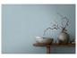 Table en bois avec vases décoratifs, bols et branches séchées contre un mur bleu.