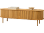 Buffet en bois clair avec portes coulissantes, livres et bol décoratif.
