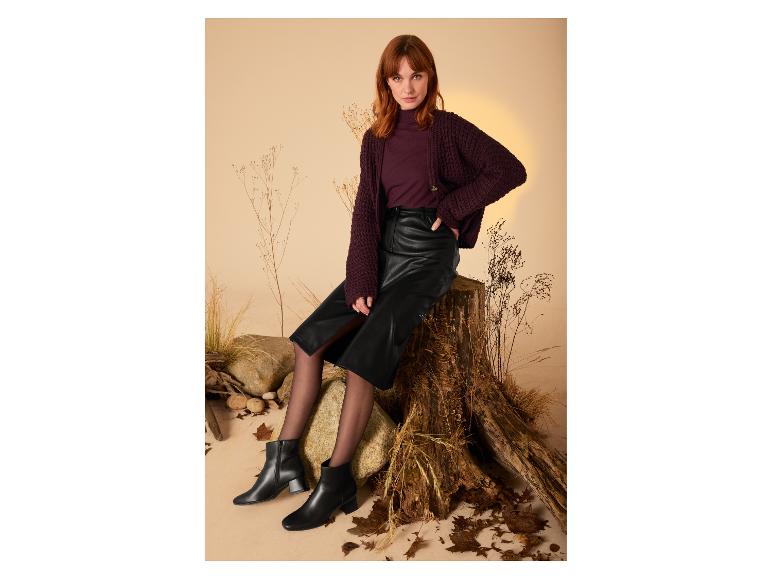 Femme en pull violet et jupe en cuir noir portant des bottines noires.
