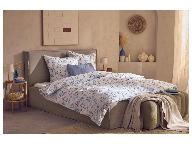 Chambre avec lit double, parure de lit à motifs bleus et blancs et table de chevet en bois.