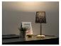 Une lampe de table noire avec un pied en bois sur un plateau de table foncé.