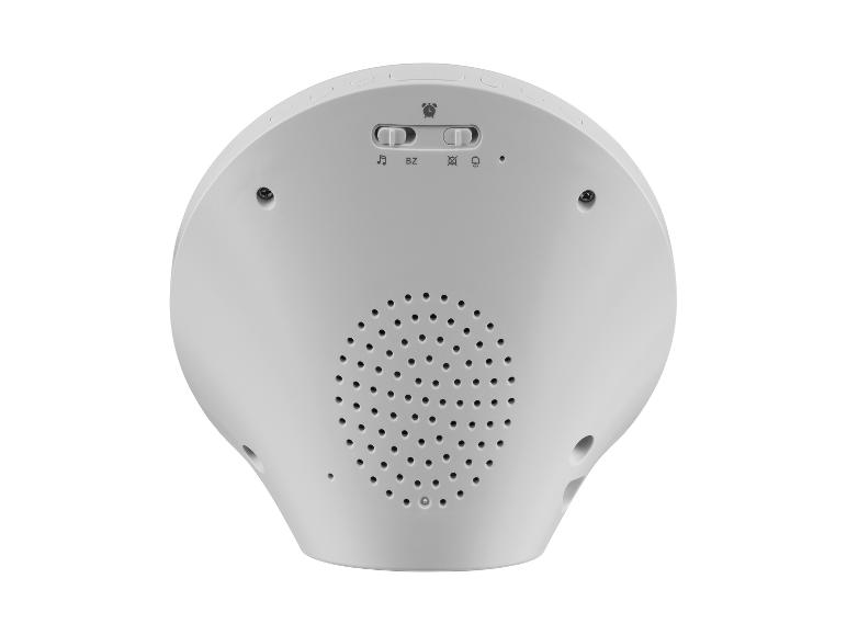 Vue arrière d'un réveil blanc avec haut-parleur, interrupteurs et boutons.