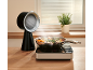 Ventilateur de table noir et plaque à induction avec une poêle de légumes sur un comptoir en bois.