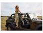 Jeep et vêtements : une femme en pantalon zébré près d'un Jeep vert.