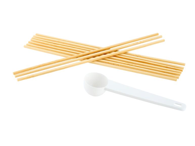 Bâtonnets en bois et cuillère doseuse blanche sur fond blanc.